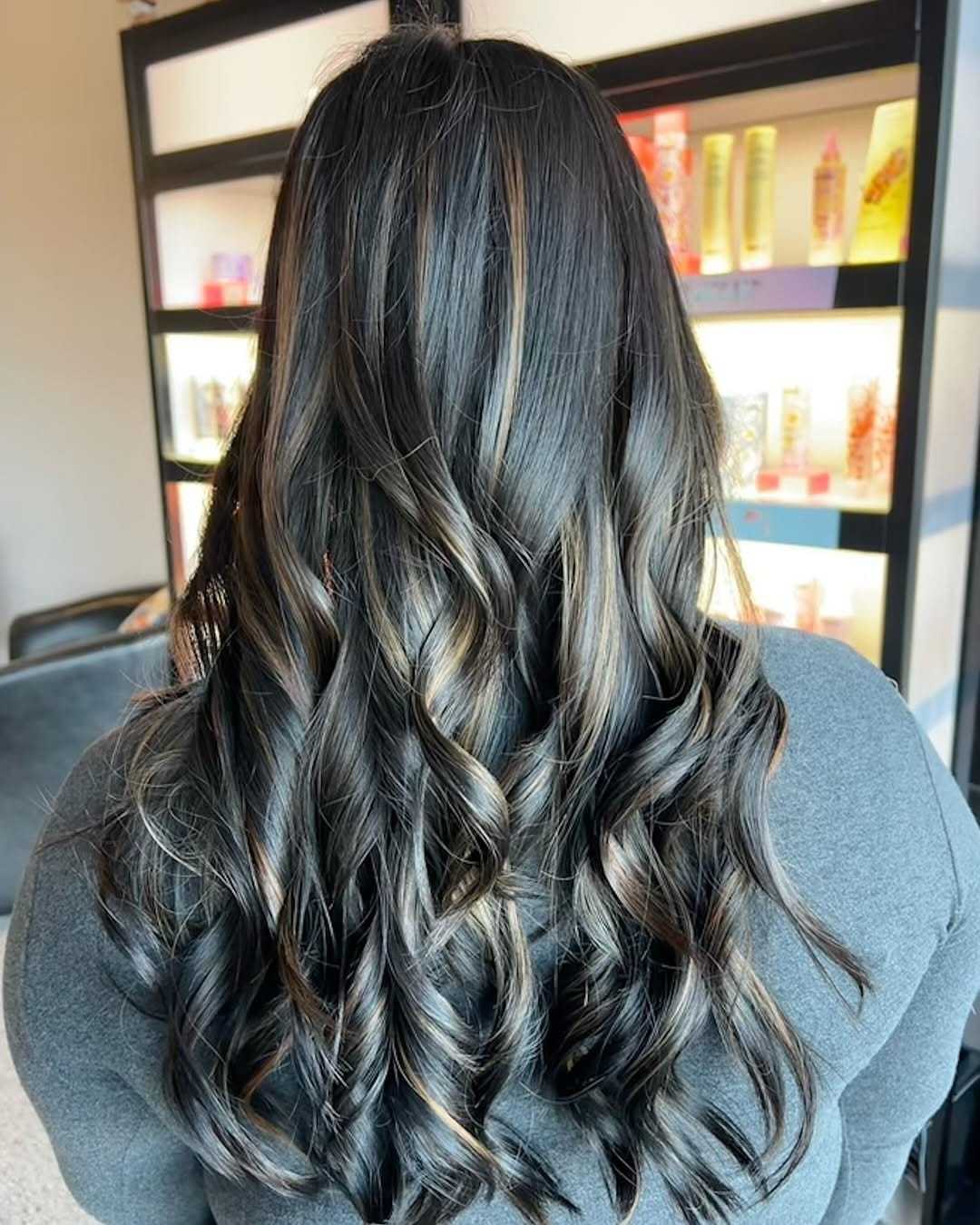 Long wavy hair with highlights in a beauty salon setting.