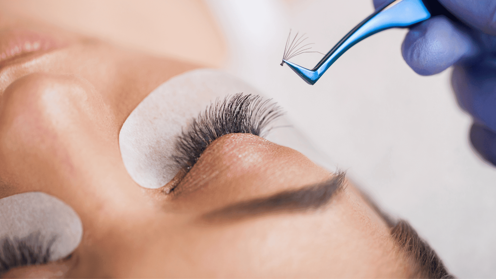 Close-up of eyelash extension application on a client's eye with protective pads in place.