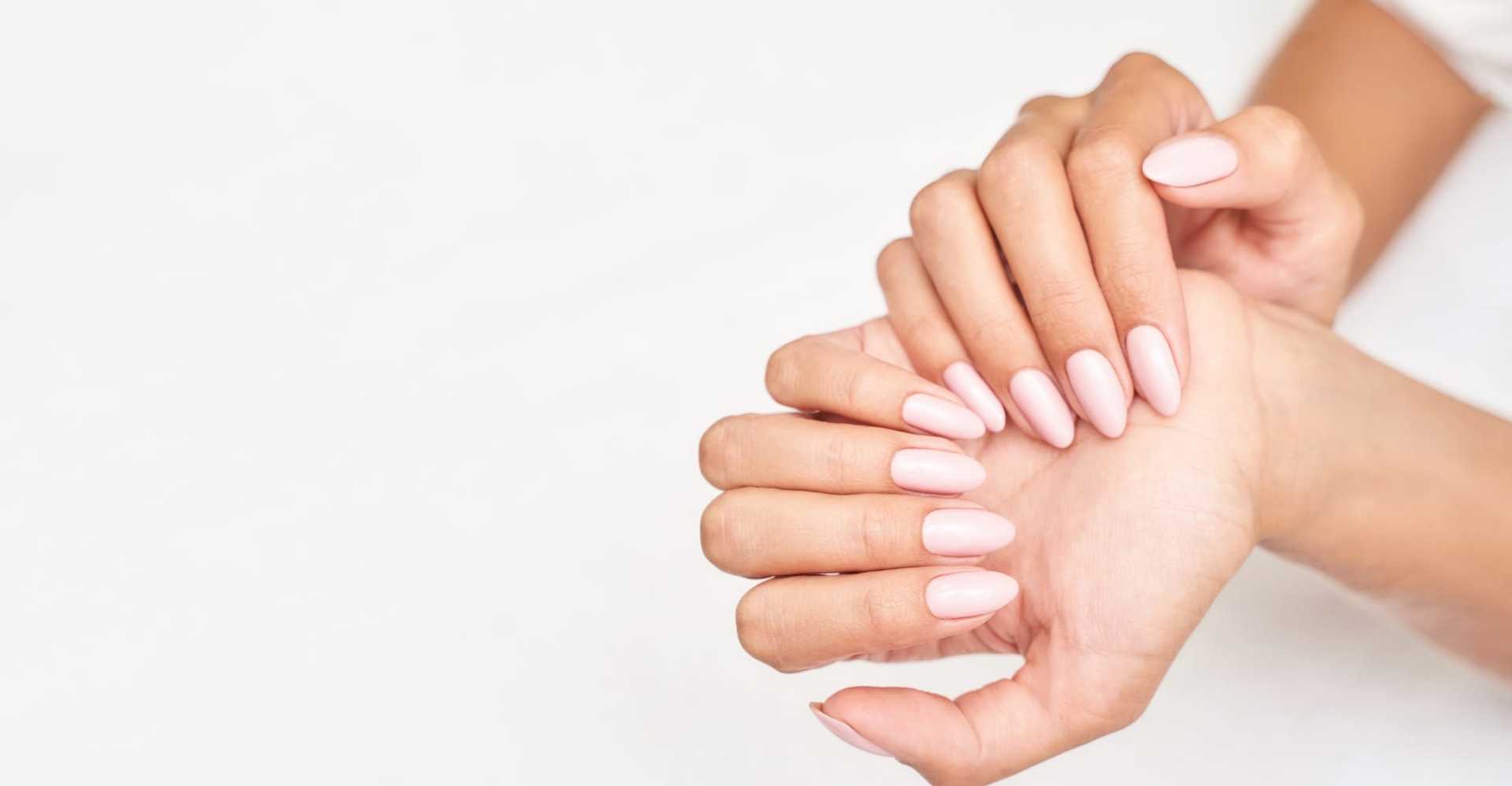 Soft pink manicured hands, elegantly posed against a light background.